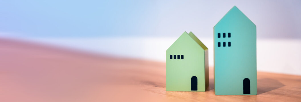 Paper house models on office desk with documents and calculator representing real estate business, property investment, and decision to buy or sell an apartment.