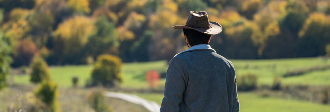 Man standing at the edge of a valley road, observing the scenic landscape ahead, reflecting contemplation, adventure, and connection with nature.