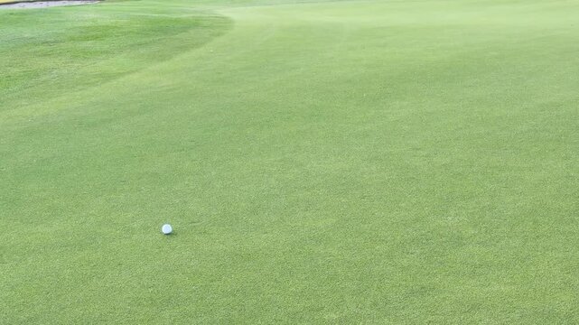 Golf Ball Rolling Across a Putting Green Toward the Hole at Sunset