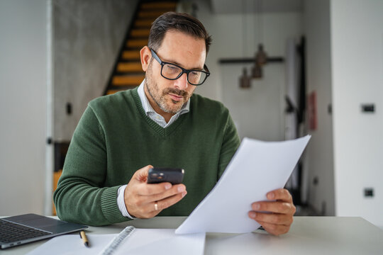 Man multitasking working from home using phone and documents