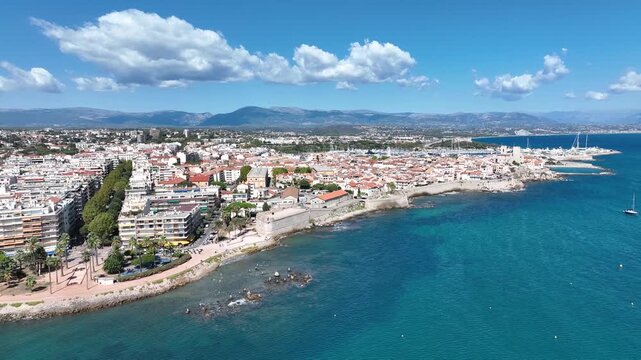 Aerial view of the gorgeous Antibes coastline, showcasing the old city walls, harbor, and the contrast of urban structures against the clear turquoise sea, Antibes, France.