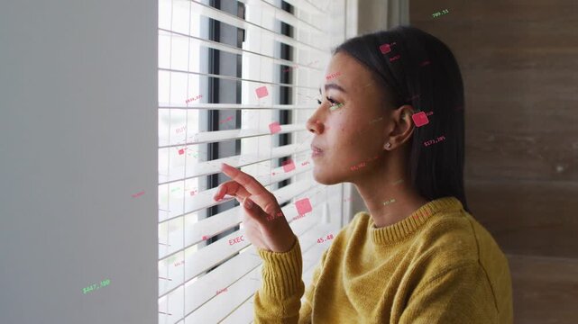 Mid-adult woman touching blind slat peering outside for monitoring while tech data markers moving