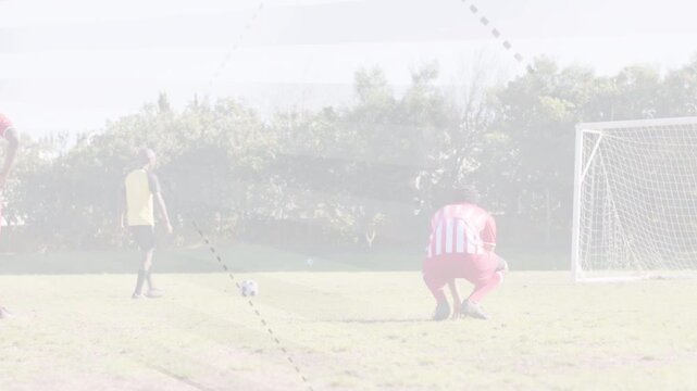 Yellow-bib player placing ball for penalty kick, dashed overlay guiding keeper and defenders