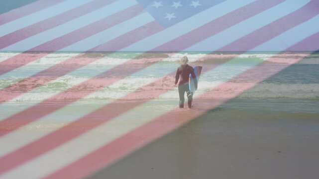 Vertical video: Senior surfer wading to surf with board pausing preparing to surf flag overlaying
