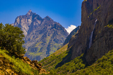 Fototapeta premium Majestic mountain peaks with waterfall and greenery
