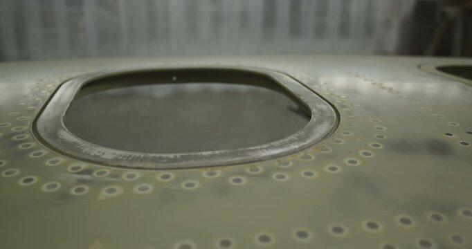 Close up of an oval window cutout in a riveted metal aircraft panel during construction