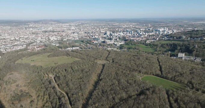 Aerial view of a forest foreground contrasting with a dense urban cityscape in the background, highlighting the blend of nature and urbanity, Nancy, France.