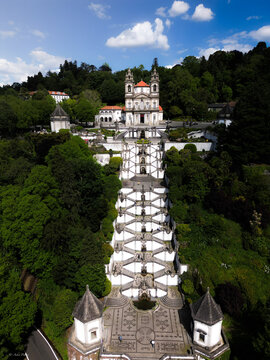 Aerial view of Bom Jesus do Monte's monumental staircase cascading through verdant trees towards the ornate church, Braga, Braga, Portugal.