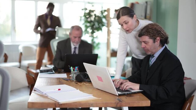 Female manager helps man solve a problem on laptop in the company office. High quality 4k footage