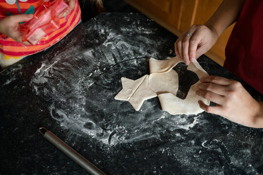 Hands of child and teenage sister using a star shaped cookie cutter on pastry