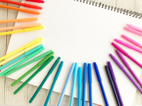 お絵描きや文房具、学校の準備・クリエイティブなアイデアを表現・白いスケッチブックを囲むカラフルなペン