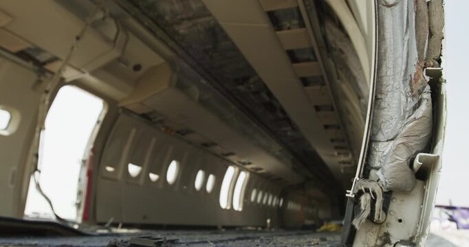 Low angle view along the side of a disassembled aircraft fuselage showing the interior structure