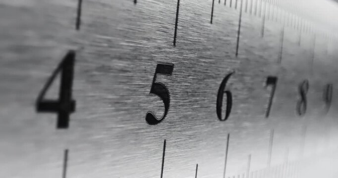 Slow Pan Over Metal Ruler. Smooth slow movement across extreme close-up of metallic ruler with black numbers and brushed surface.