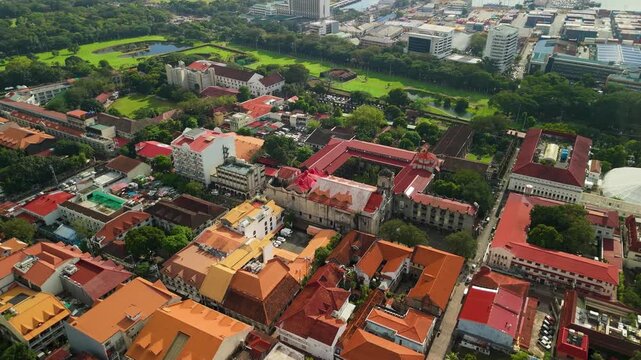 Aerial flyover above Intramuros Manila capturing San Agustin Church baroque complex, Casa Manila colonial rooftops, National Museum dome, and golf course from above