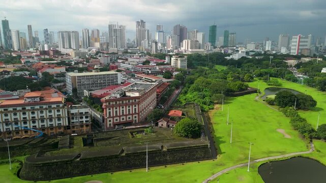 Drone aerial parallax over Baluarte de San Diego fortress walls in Intramuros Manila revealing historic colonial architecture against modern city skyline