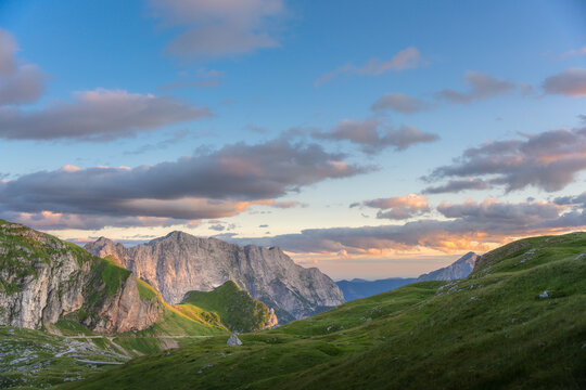 Aerial view of jagged mountain peaks pierce the horizon under a serene sky painted with hues of dawn, Log pod Mangartom, Bovec, Slovenia.
