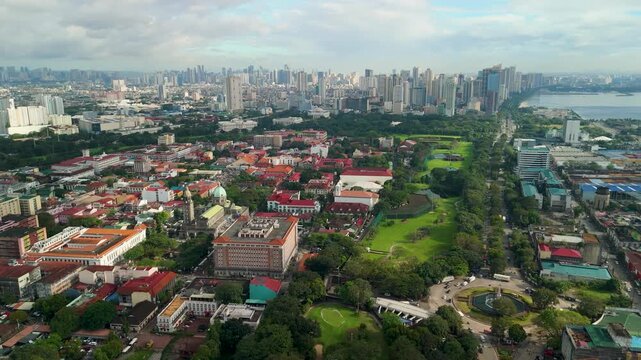 High altitude parallax drone shot over historic Intramuros walled city in Manila revealing Spanish colonial rooftops, lush golf course, Manila Bay, and sprawling Metro Manila skyline