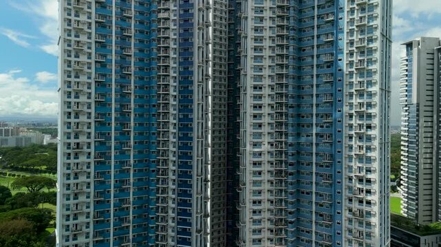 Cinematic drone ascending shot moving vertically along glass facade of Trion Towers in Bonifacio Global City Manila showcasing modern residential skyscrapers and urban development
