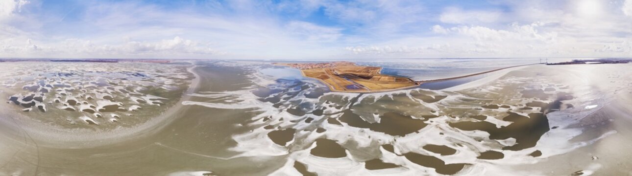 Aerial view of amazing shapes in thawing ice on lake Gouwzee, in front of the old island Marken, in 360 degrees panorama, Noord-Holland, Netherlands.