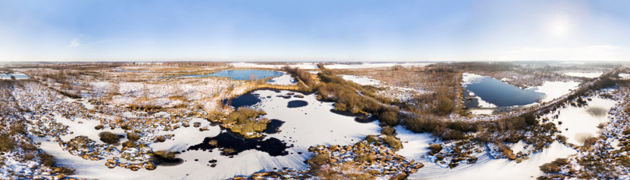 Aerial view of winter landscape with peat bogs, frozen lakes, trees and bushes in raised bog area covered with snow, in 360 degrees panorama, Haaksbergerveen, Twente, Overijssel, Netherlands.