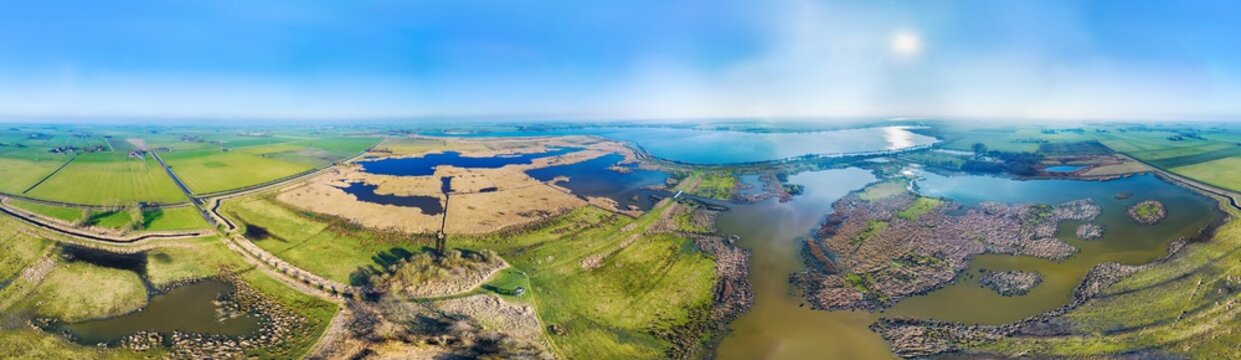 Aerial view of newly developed nature reserve at the countryside with wetlands, reedland, marshes and lakes, in 360 degrees panorama, Tetjehorn, 't Roegwold, Groningen, Netherlands.