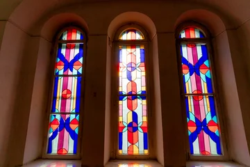 A beautiful stained glass window featuring an abstract design of various geometric shapes in a kaleidoscope of bright, translucent colors, creating a captivating visual effect. © Michael