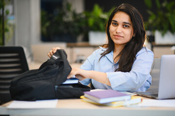 Obraz premium Indian female student taking books from backpack