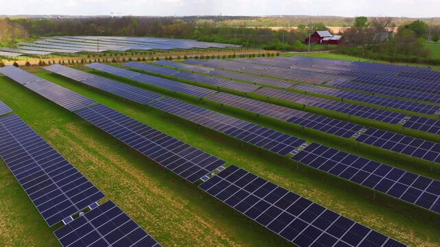 Aerial view of solar panels contrasting with the green grass and a red barn in the background, Lebanon, Ohio, United States.
