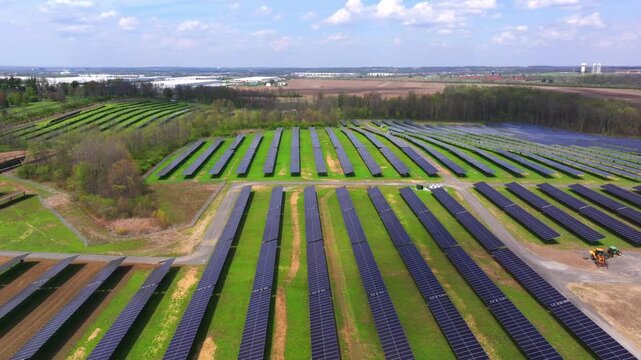 Aerial view of rows of solar panels stretching across the green landscape, capturing sunlight, Lebanon, Ohio, United States.