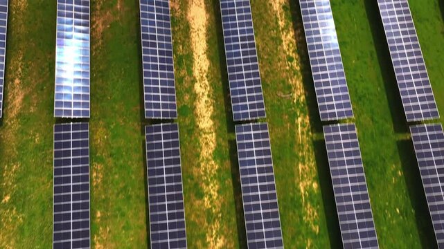 Aerial view of rows of solar panels glistening on green grass, creating a geometric pattern against the backdrop of the landscape, Lebanon, Ohio, United States.