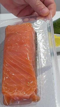 Close-up of fresh raw salmon fillet on a cutting board in a professional kitchen. Clean preparation and vivid texture of pink fish meat