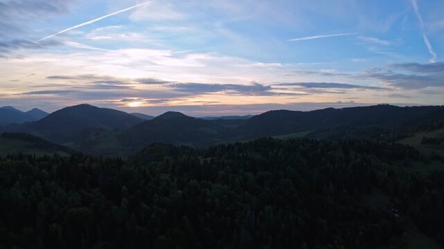Panoramic view of moody twilight over forested hills and cloudy sky