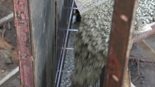 Construction crew pours concrete into formwork for building project in urban area