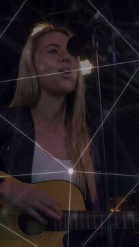 Vertical video: Singer moving to mic on stage playing guitar, singing music with overlay over face