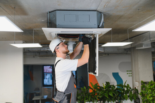 Hvac technician installing air conditioning system in office