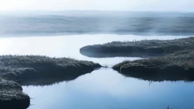 Showing central channel flanked by peat tussocks as breeze stirring ripples at marsh, mist forming