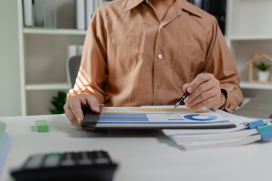 Person reviewing budget report and financial data on documents, analyzing charts and numbers, representing accounting work, financial planning, and business decision making.