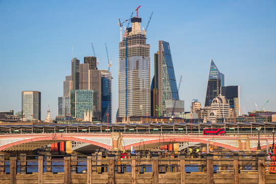 London skyline with modern city skyscrapers and industrial cranes rising behind Blackfriars Bridge on the River Thames