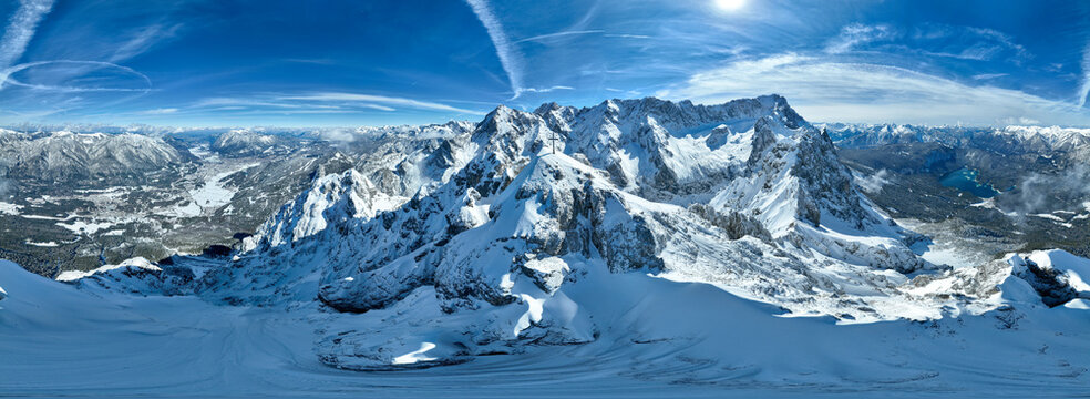 Aerial view of snow-capped peaks pierce the azure sky, casting long shadows over the pristine white landscape, Garmisch-Patenkirchen, Bavaria, Germany.