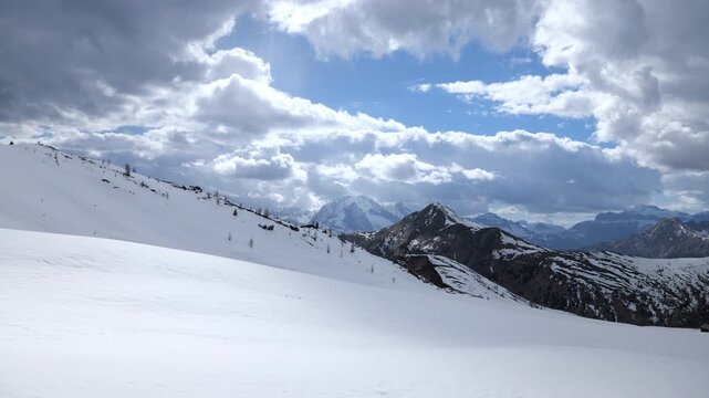 Winter mountain landscape. Snow-capped Dolomites with fast-moving clouds changing light on the snow surface