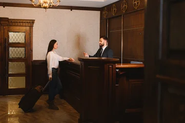 Fotobehang Hotel chique Woman checking in with hotel receptionist  © Serhii