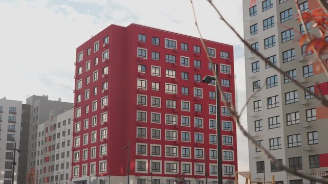 Large red multi-storey apartment building and autumn tree without leaves