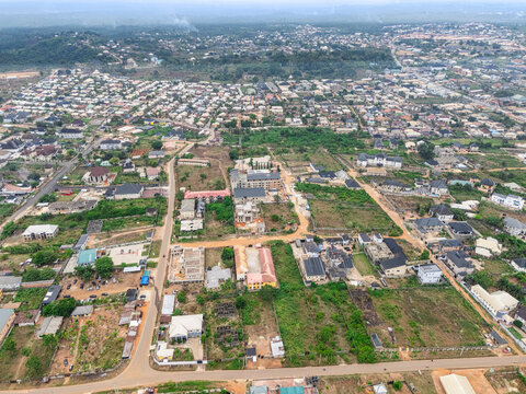 Aerial view of houses and vegetation interspersed with patches of bare earth, creating a textured mosaic under a vast sky, Umuahia, Abia, Nigeria.