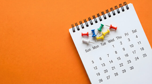 calendar with push pins on orange background