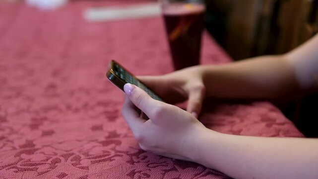 Woman in red dress using smartphone at wooden table dark red room wine drink social media ordering food online