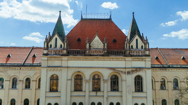 Aerial view of the grand, ornate facade of a historic building featuring a striking red roof against a bright blue sky, Zrenjanin, Vojvodina, Serbia.