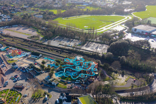 Aerial view of Splashdown Waterpark's vibrant turquoise slides contrasting with the surrounding buildings and greenery, Paignton, England, United Kingdom.