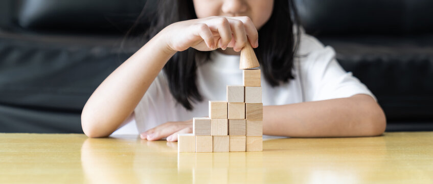 Wooden blocks rising steps child behind patience effort planning strategy step progress focus control consistency logical development achievement.