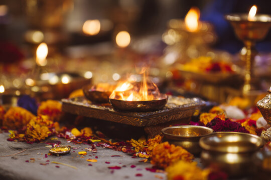 Sacred fire altar prepared for hindu wedding ceremony with flower petals, brass bowls and ritual items arranged neatly, warm lighting,
