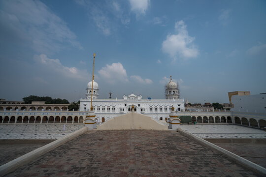 View of the white Gurdwara Janam Asthan gleams beneath a vast blue sky, its intricate architecture a testament to heritage, Nankana Sahib, Punjab, Pakistan.